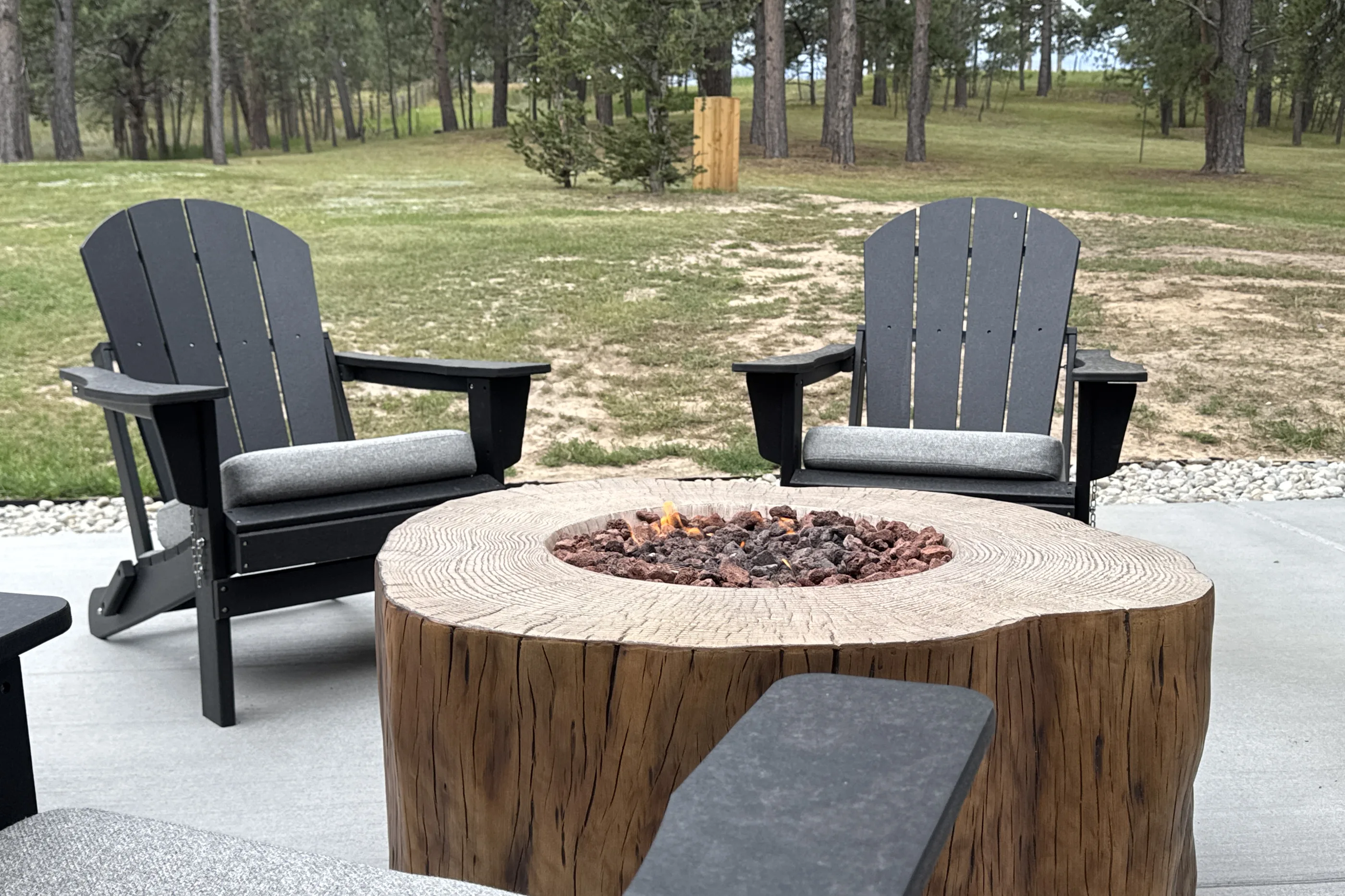 Adirondack chairs around a lit fire pit beside a Stoddard deck