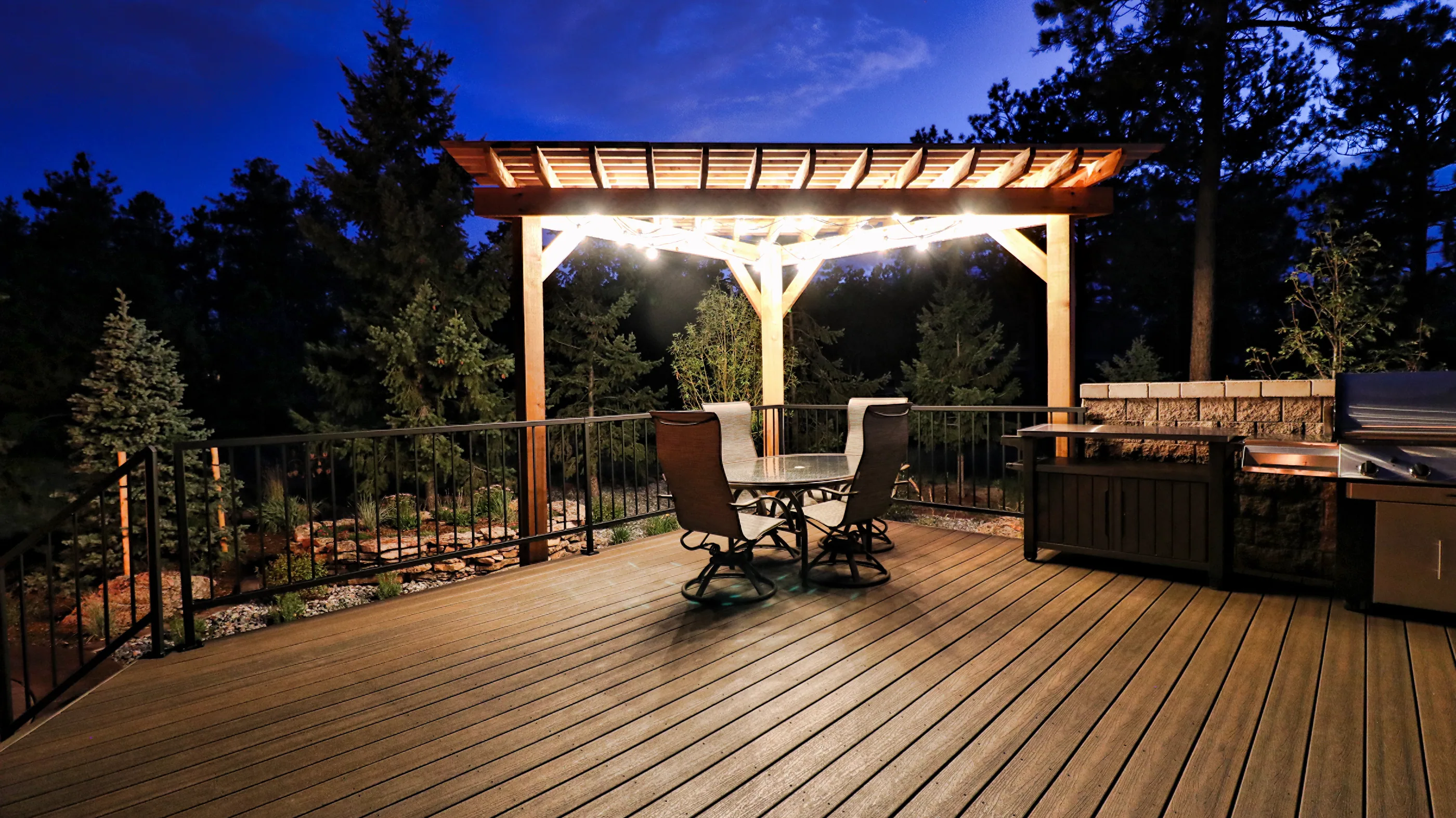 A lit cedar pergola over a composite deck at dusk on a Stoddard project