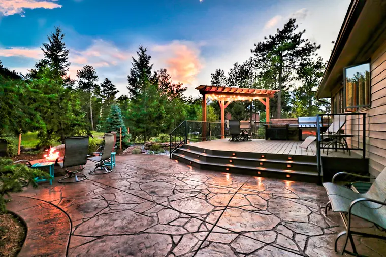 Classic railing around a deck at dusk beside a pergola and fire pit