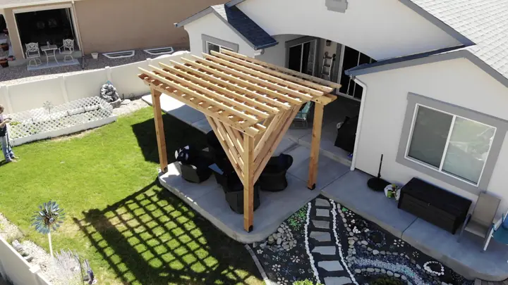 A freestanding cedar pergola over patio seating on artificial turf, seen from above