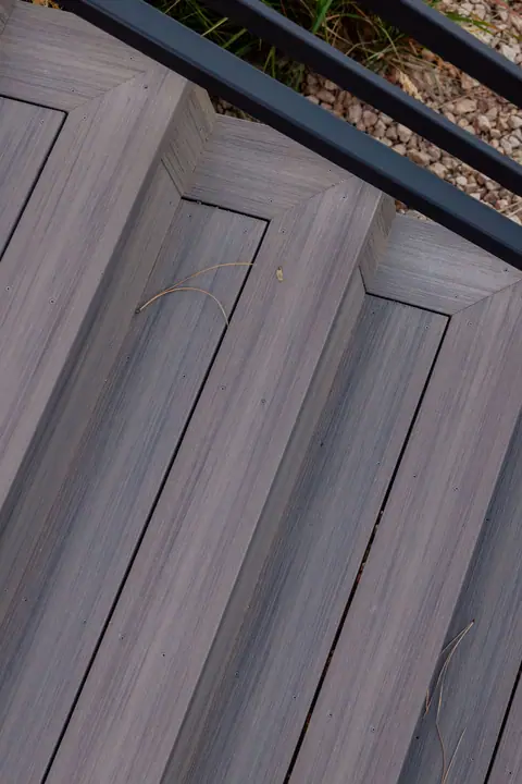 Close view of composite stair treads with mitered picture-frame borders and black railing